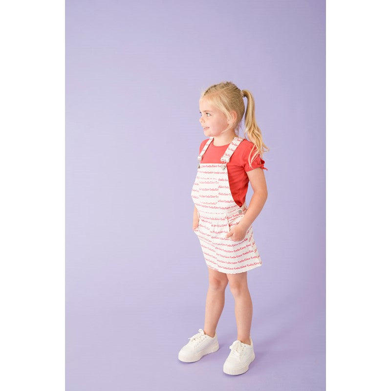 Flottes Salopette-Kleid in weiß mit rotem All Over Druck Ciao Bella. Die verstellbaren Träger sind individuell anpassbar.