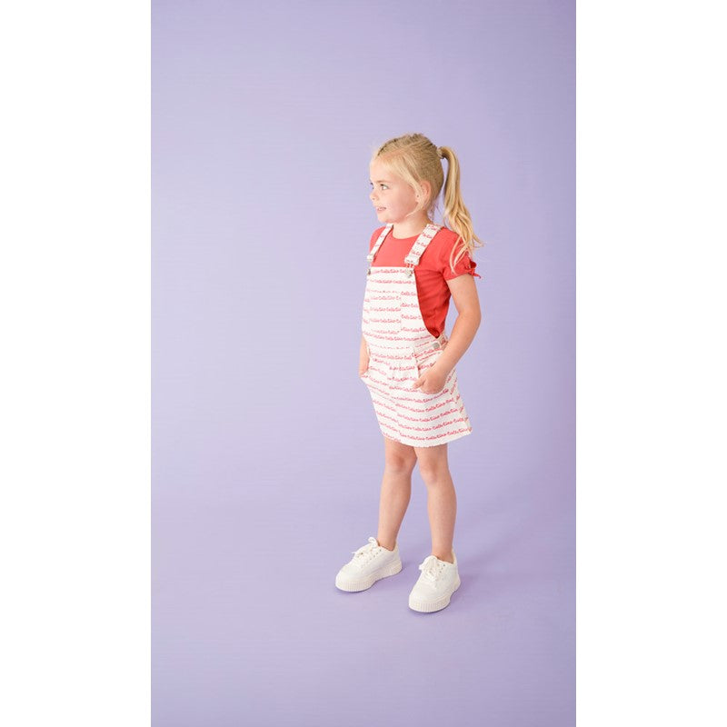 Flottes Salopette-Kleid in weiß mit rotem All Over Druck Ciao Bella. Die verstellbaren Träger sind individuell anpassbar.